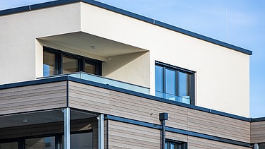 Nahaufnahme der Fassade, einer Kombination aus Holz bei den unteren Etagen und Putz für das oberste Stockwert