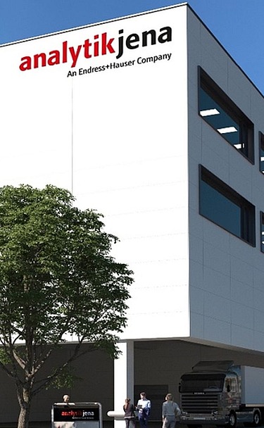 Picture shows an office building under a blue sky with two trees in front of it
