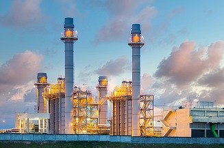 A picture of a factory complex with towers at sunrise