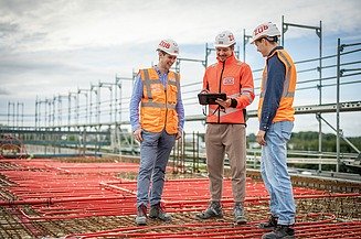 Photograph of three workers wearing safety clothing on a building site