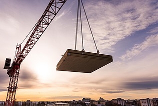 Foto des Collegium Academicums in Heidelberg während der Montage. Man sieh ein LENO-Holzelement schwebend am Kran.