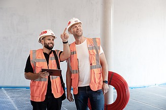 Two workers in high-visibility clothing on a building site, talking to each other