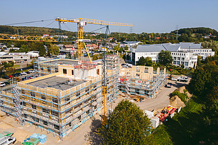 Foto der Uni Witten von außen. Man sieht die Montage großer Holzelemente aus der Vogelperspektive