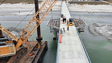 Langer Steg oder Brücke, die von Land ins Meer führt, mit Verbindung zur Baustelle der künstlichen Insel vor Prerow.
