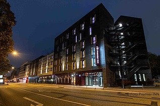 Nachtansicht des Hotels PREMIER INN Hamburg-St. Pauli mit beleuchteter Fassade