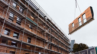 Foto des Collegium Academicums in Heidelberg während der Montage. Man sieh ein LENO-Holzelement schwebend am Kran.