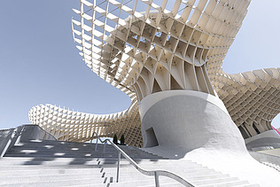 Foto einer großen Treppe. Oben sieht man die pilzartige Holzkonstruktion von Metropol Parasol Sevilla.
