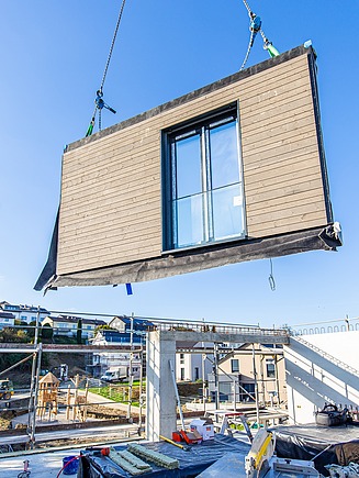 Photo of prefabricated wooden exterior wall element on crane, ready for installation