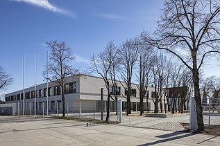 Außenaufnahme der Vinzenz-Pallotti-Schule in Friedberg. Man sieht ein großes, weißes Gebäude mit Flachdach.